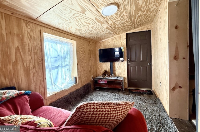 sitting room featuring vaulted ceiling and wooden walls