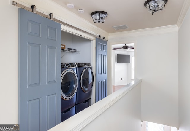 laundry area with ornamental molding, laundry area, a barn door, and washing machine and clothes dryer