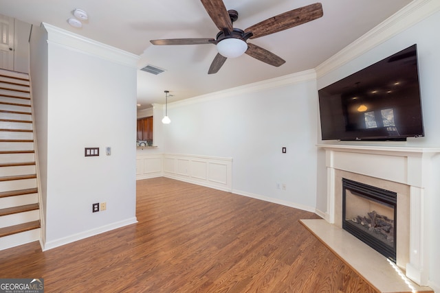 unfurnished living room featuring visible vents, a premium fireplace, ornamental molding, and wood finished floors