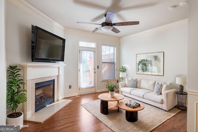 living area with ceiling fan, ornamental molding, wood finished floors, and a high end fireplace