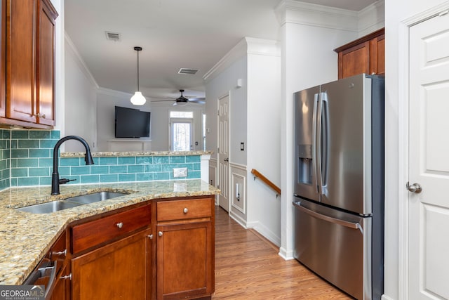 kitchen featuring stainless steel refrigerator with ice dispenser, a sink, visible vents, and crown molding