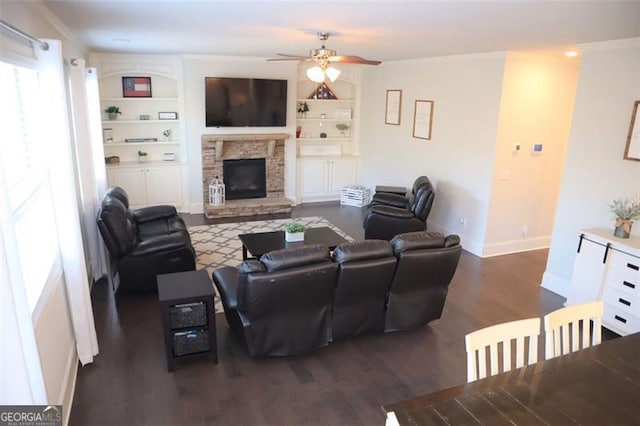 living area with baseboards, built in features, a ceiling fan, wood finished floors, and a fireplace