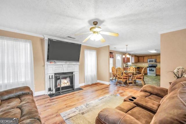 living room featuring light wood-style floors, a large fireplace, visible vents, and ornamental molding