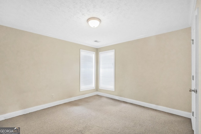 empty room featuring carpet floors, baseboards, visible vents, and a textured ceiling