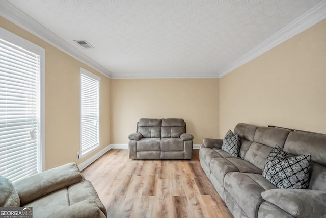 living room with a textured ceiling, light wood finished floors, visible vents, and crown molding