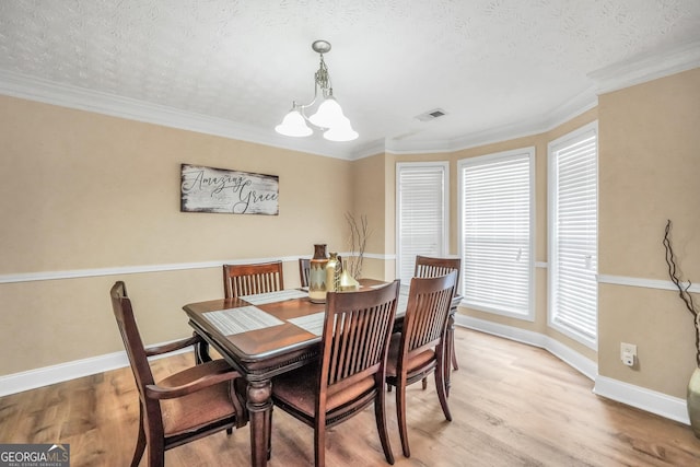 dining room featuring an inviting chandelier, light wood-style flooring, visible vents, and a textured ceiling