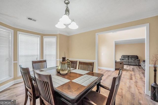 dining space featuring crown molding, a notable chandelier, visible vents, light wood-style flooring, and baseboards