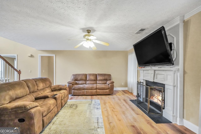 living area featuring light wood-style floors, a fireplace with flush hearth, visible vents, and baseboards