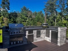 wooden deck with an outdoor kitchen and area for grilling