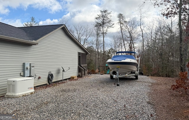 view of side of property with roof with shingles and gravel driveway