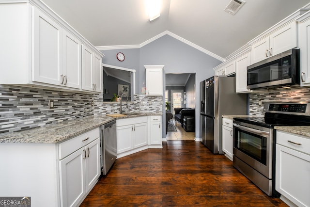 kitchen featuring visible vents, lofted ceiling, stainless steel appliances, white cabinetry, and a sink