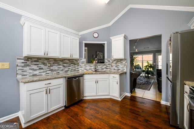 kitchen featuring stainless steel appliances, a sink, white cabinetry, vaulted ceiling, and ornamental molding