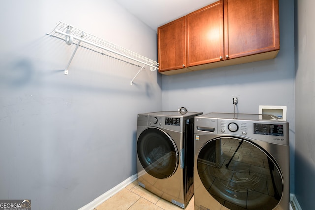 laundry area featuring baseboards, cabinet space, washing machine and clothes dryer, and light tile patterned floors