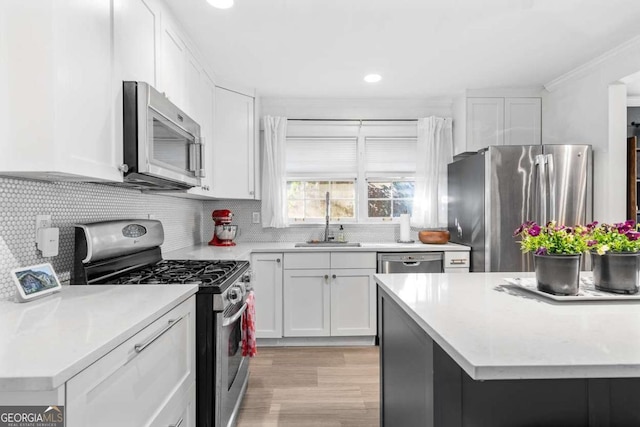 kitchen featuring stainless steel appliances, light countertops, decorative backsplash, white cabinets, and a sink