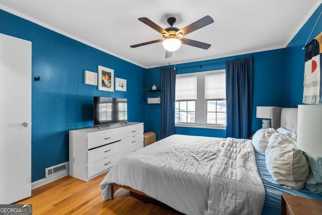 bedroom featuring baseboards, visible vents, ceiling fan, ornamental molding, and wood finished floors