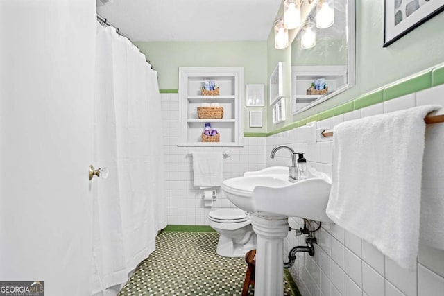 full bath featuring built in shelves, a shower with shower curtain, toilet, and tile walls