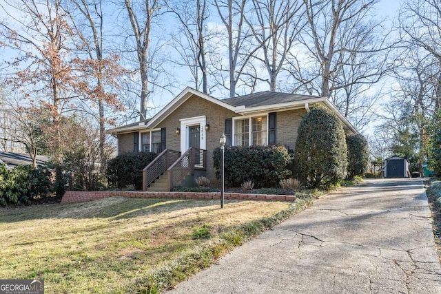 bungalow-style house with a storage shed, brick siding, an outdoor structure, driveway, and a front yard