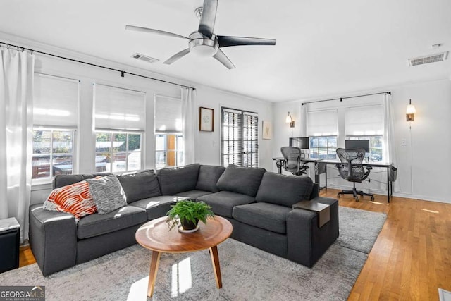 living area with visible vents, ceiling fan, and wood finished floors