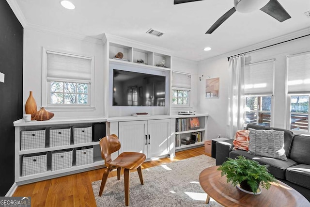 living room featuring light wood-style floors, ornamental molding, and a wealth of natural light