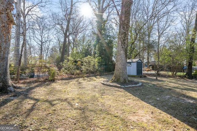 view of yard featuring an outbuilding, a shed, and fence