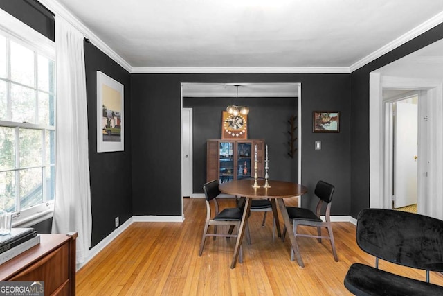 dining room with a chandelier, ornamental molding, light wood-type flooring, and baseboards