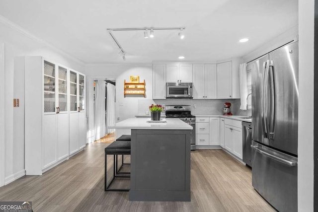 kitchen with light wood-type flooring, a kitchen island, stainless steel appliances, and light countertops