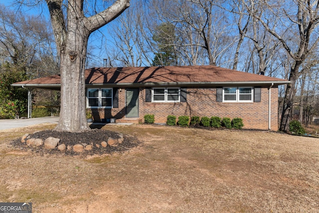 ranch-style home featuring an attached carport, concrete driveway, and brick siding