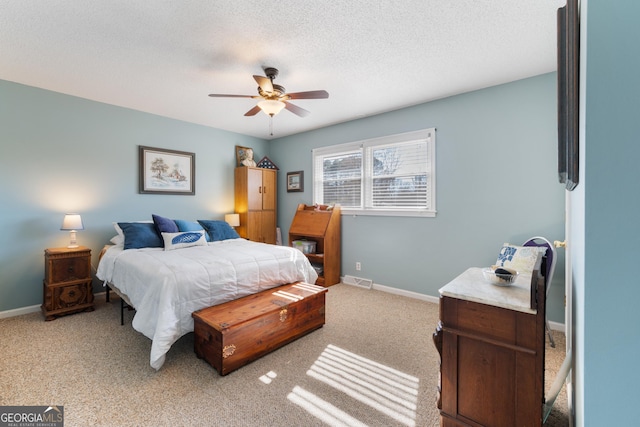 bedroom with light carpet, a textured ceiling, a ceiling fan, and baseboards