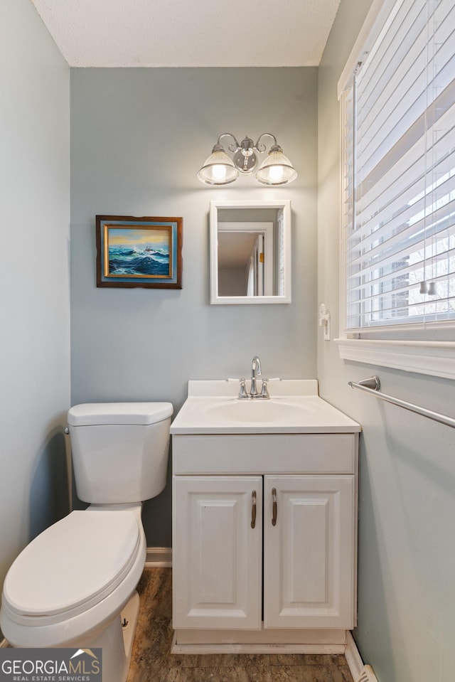 bathroom featuring baseboards, vanity, and toilet