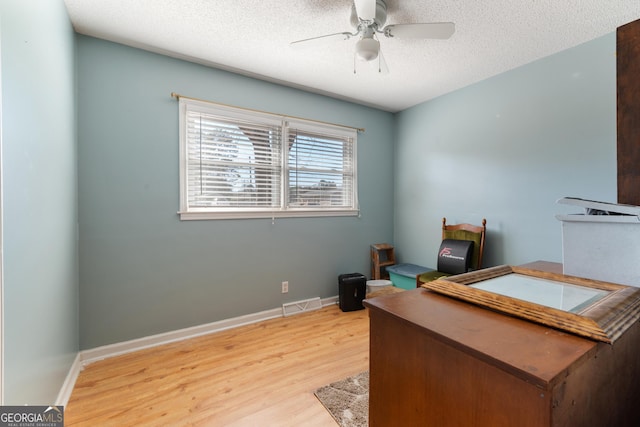 office area featuring a textured ceiling, wood finished floors, visible vents, baseboards, and a ceiling fan