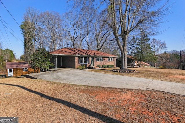 view of front of home featuring driveway, brick siding, a front yard, and an outdoor structure