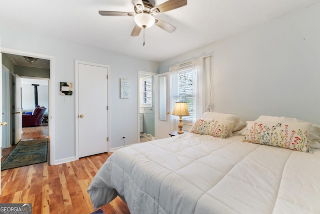 bedroom with a ceiling fan, a textured ceiling, baseboards, and wood finished floors