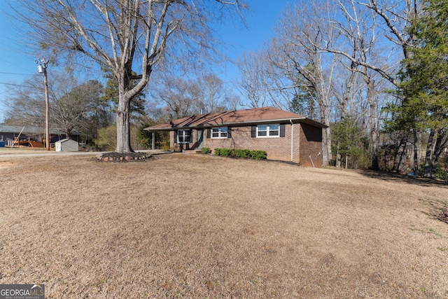 ranch-style house with a shed, a front yard, an outbuilding, and brick siding