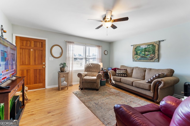 living area with light wood-style flooring, baseboards, and a ceiling fan