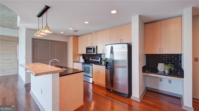 kitchen featuring a sink, hanging light fixtures, appliances with stainless steel finishes, tasteful backsplash, and dark wood finished floors