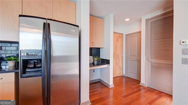 kitchen with light wood-style flooring, recessed lighting, decorative backsplash, dark countertops, and stainless steel fridge