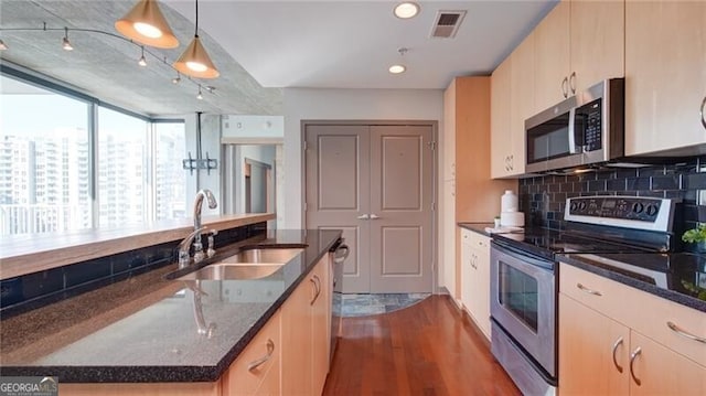 kitchen featuring stainless steel appliances, visible vents, a sink, and dark stone countertops