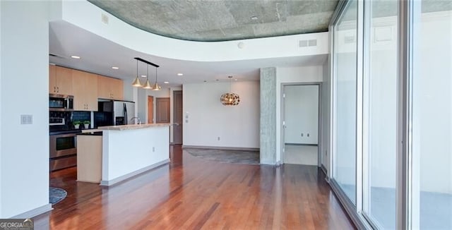 kitchen with stainless steel appliances, visible vents, light brown cabinetry, a kitchen island with sink, and wood finished floors