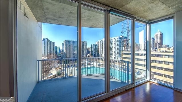 interior space with a wall of windows, a city view, and wood finished floors