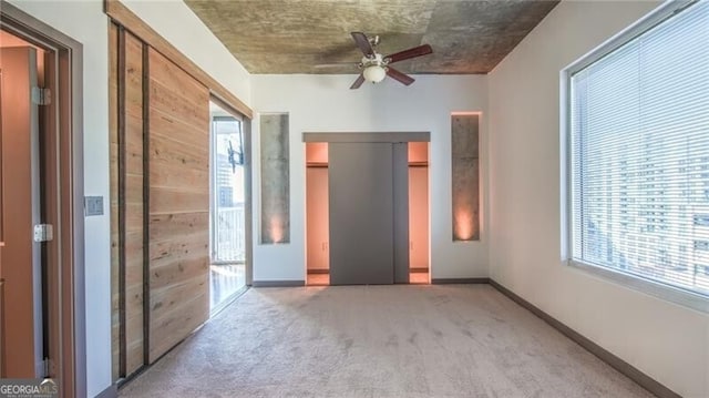 unfurnished bedroom featuring a ceiling fan, baseboards, multiple windows, and carpet flooring