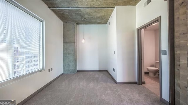 empty room with carpet, visible vents, and baseboards