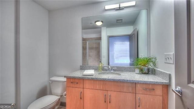 bathroom with a stall shower, vanity, and toilet