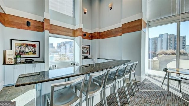 kitchen with a view of city, a breakfast bar, dark stone countertops, and white cabinets