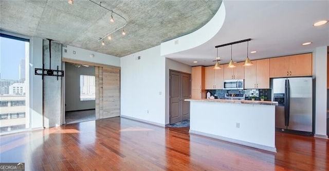 kitchen featuring pendant lighting, dark wood finished floors, stainless steel appliances, decorative backsplash, and a kitchen island