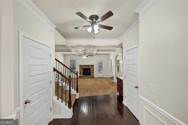 entryway featuring beam ceiling, dark wood-style flooring, a fireplace with raised hearth, stairway, and coffered ceiling