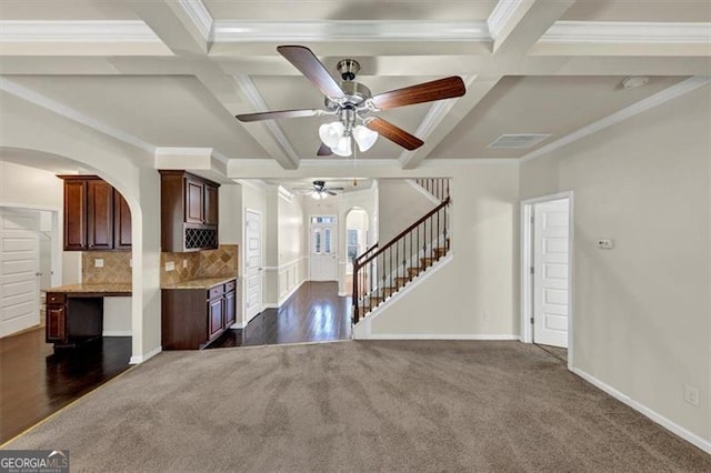 unfurnished living room featuring stairway, arched walkways, coffered ceiling, and beamed ceiling