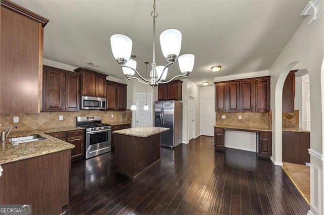 kitchen with light stone countertops, appliances with stainless steel finishes, dark wood-type flooring, and a sink