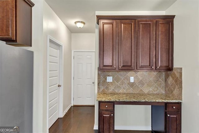 kitchen with dark wood-style flooring, baseboards, freestanding refrigerator, light stone countertops, and tasteful backsplash