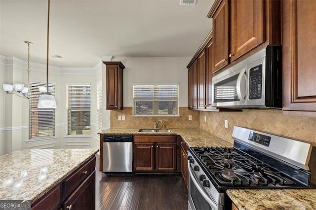 kitchen featuring appliances with stainless steel finishes, a sink, decorative backsplash, and light stone countertops