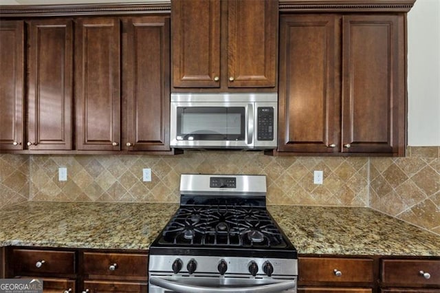 kitchen with light stone counters, stainless steel appliances, and decorative backsplash